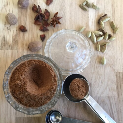 Spice mix in a small glass jar with a measuring spoon on the side.