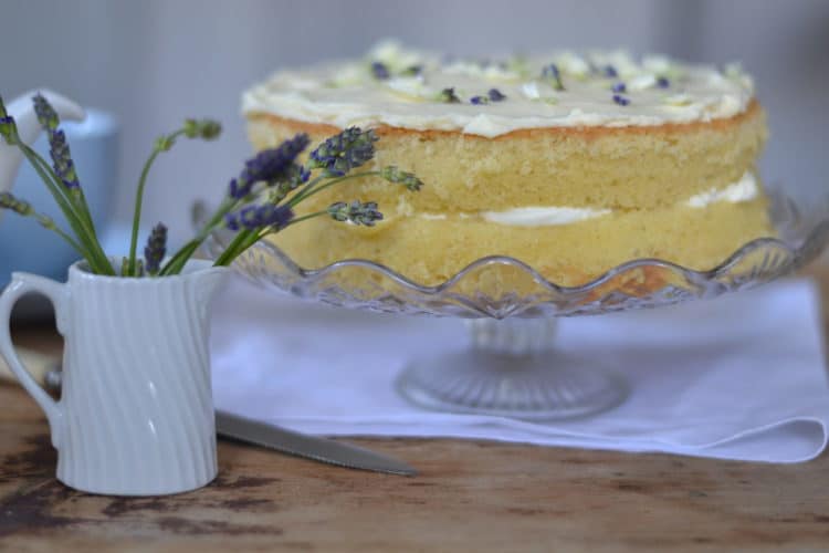 Cake on a cake stand with a jug of flowers