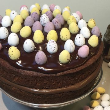 Chocolate Cake Decorated with sugar coated eggs. On a glass cake stand.