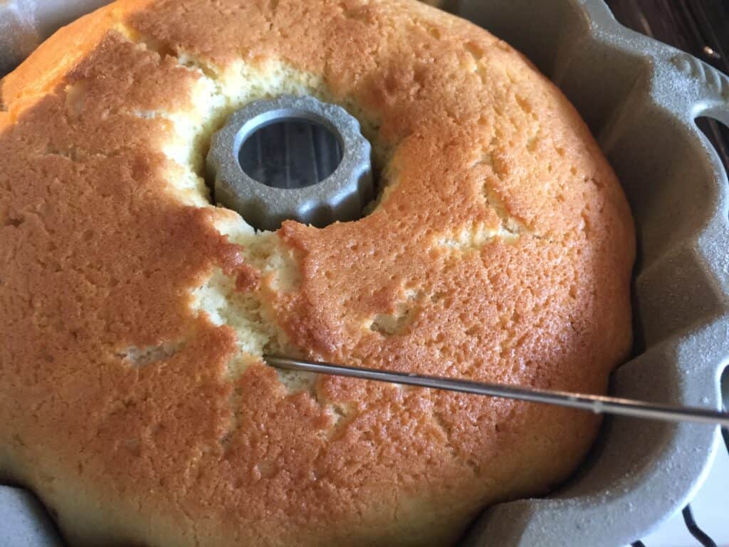 Vanilla bundt cake being tested with a skewer