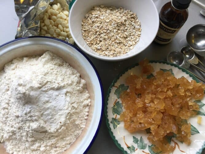 Bowls containing ingredients for ginger, oat and white chocolate cookie bars