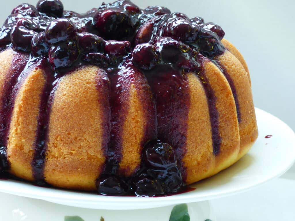  Bundt cake with a blueberry sauce on a white plate.