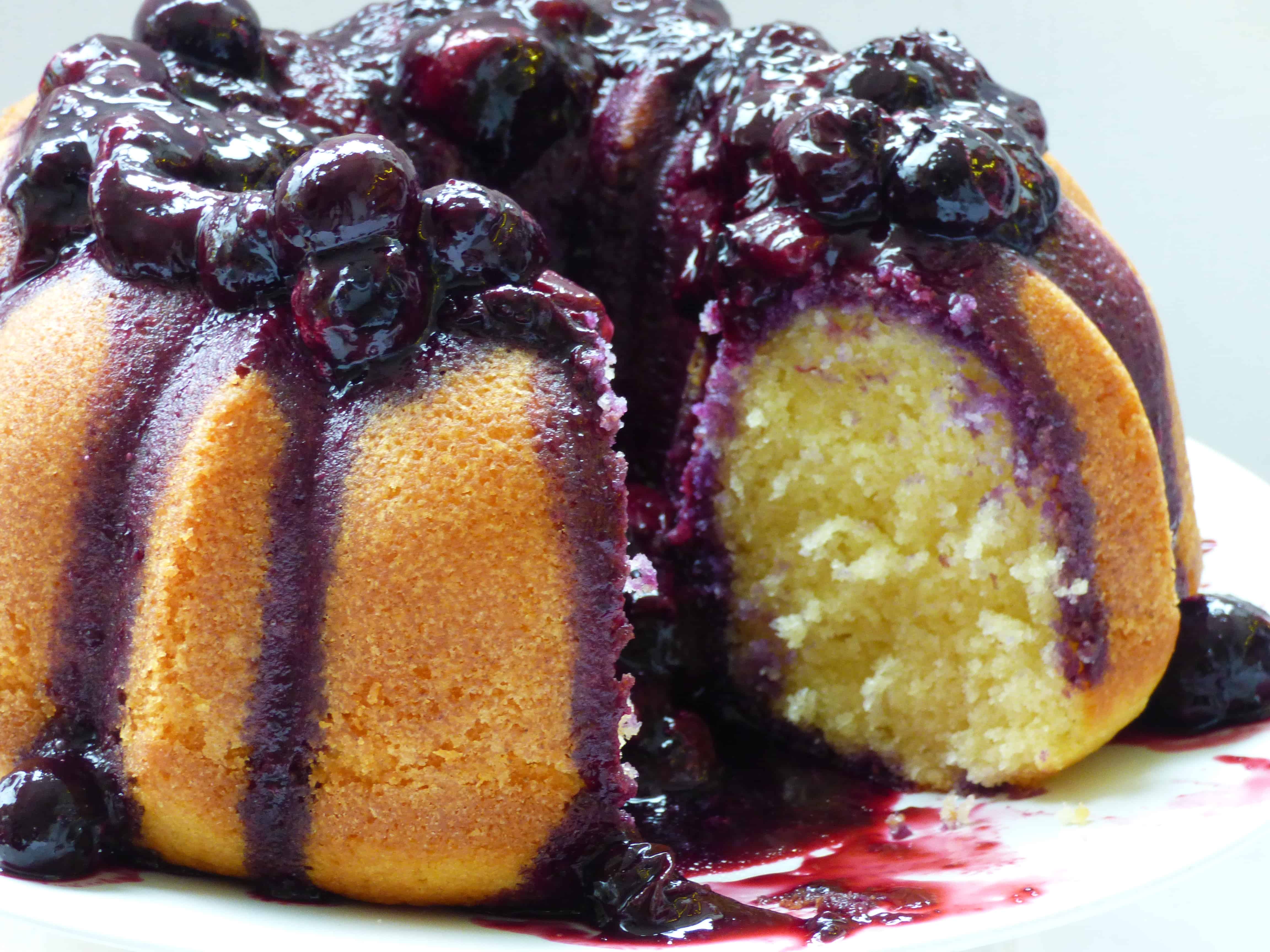 Vanilla Bundt Cake with a blueberry sauce on a white plate.
