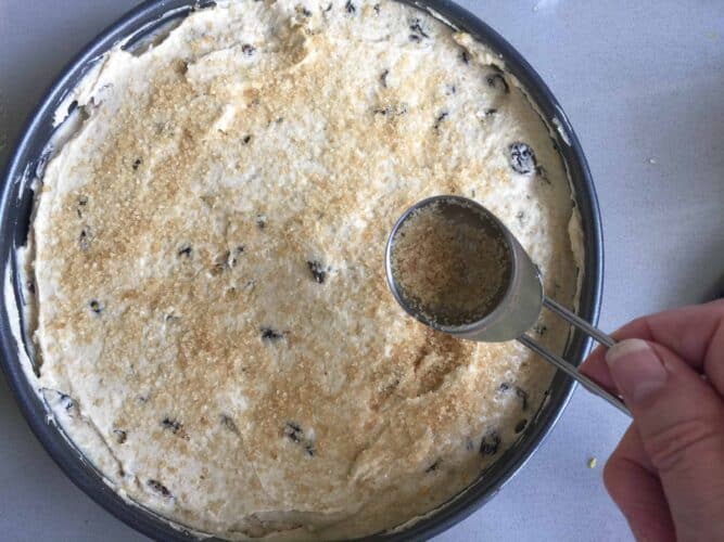Dusting cake batter with brown sugar in a cake tin before baking.