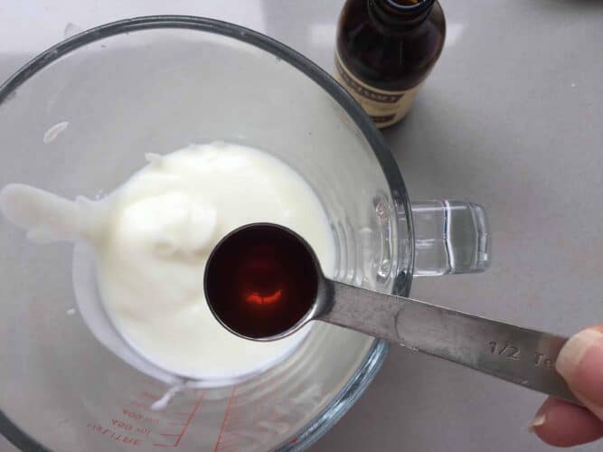 Vanilla extract being added to a jug of buttermilk