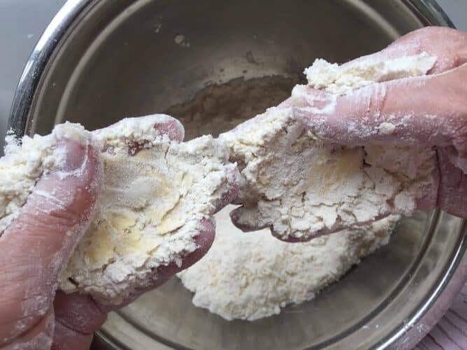 Rubbing butter and flour between fingers and thumbs over a bowl