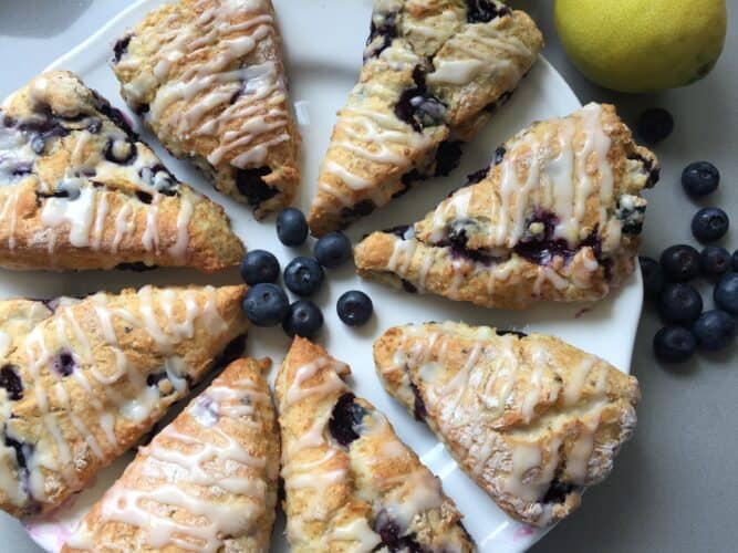 8 portions of Lemon glazed blueberry scones on a white plate. 