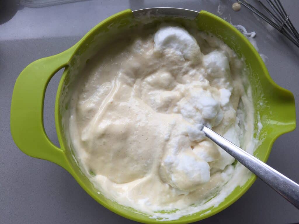 Egg whites and cake batter in a green bowl