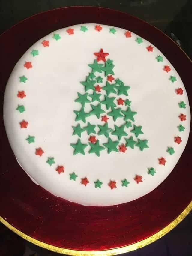 Fondant covered cake with wreath of red and green stars and a Christmas tree made out of fondant stars