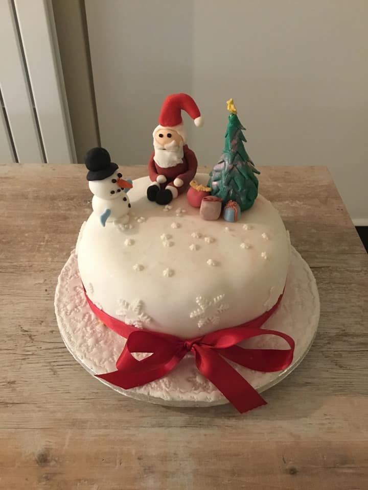 Cake with Fondant cake toppers in the shape of a snowman, Santa, and a christmas tree with presents