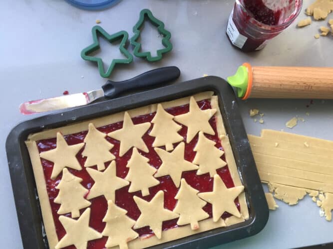 Cut out shapes of pastry on top of a layer of jam in a baking sheet.