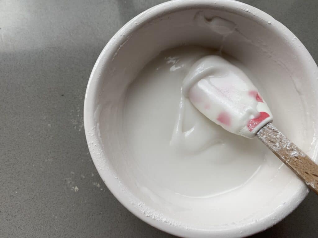 Water icing in a small white bowl with a small spatular