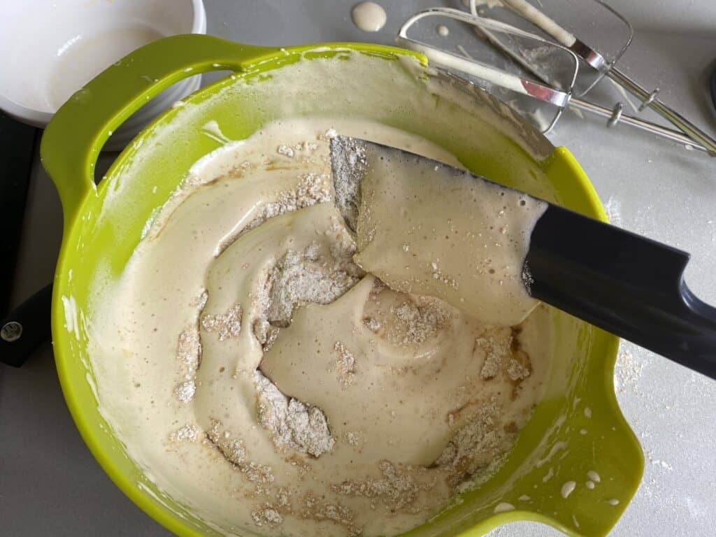 Foleding flour into cake batter in a green bowl