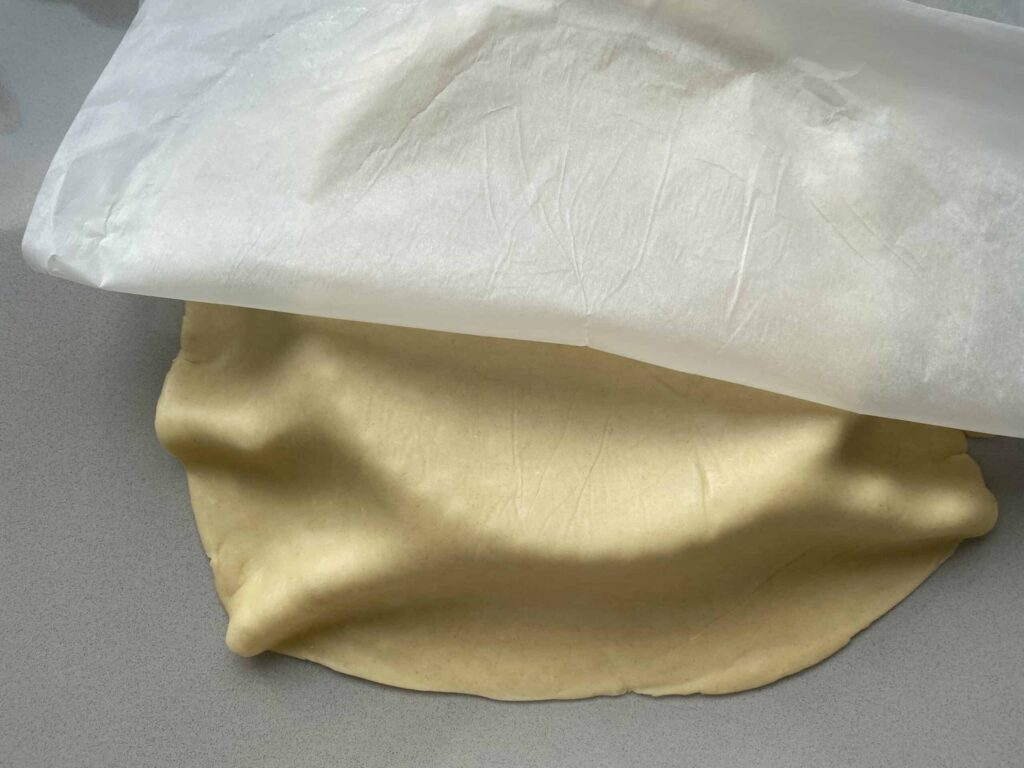 Baking parchment partially covering a sheet of rolled out pastry