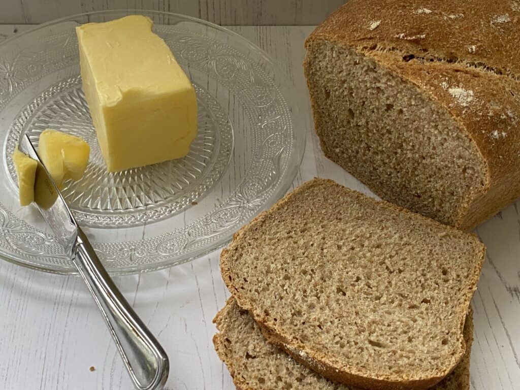 Butter on a glass plate. Slices of brown bread