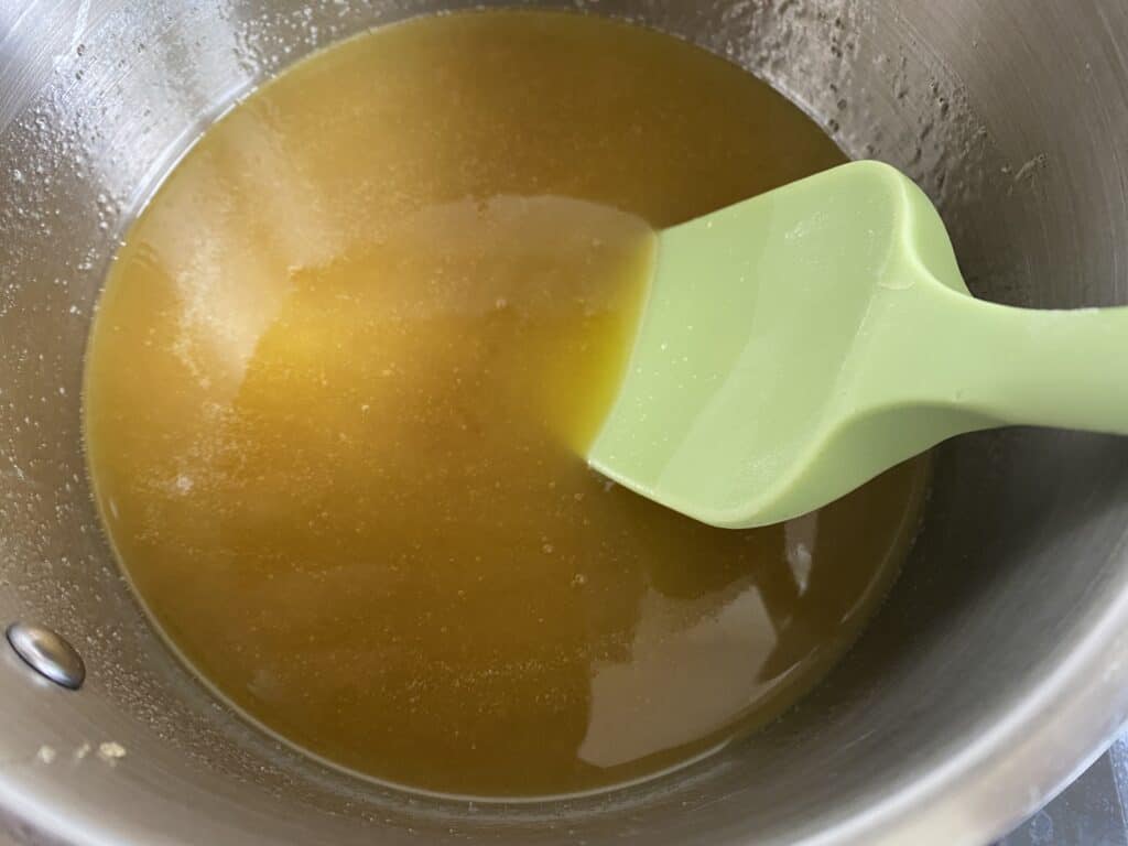 Melted butter, syrup and sugar in a pan with a green spatular