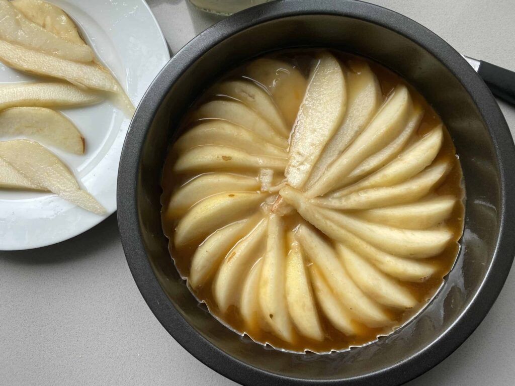 Overhead shot of sliced pears and caramel sauce in a tart tin.