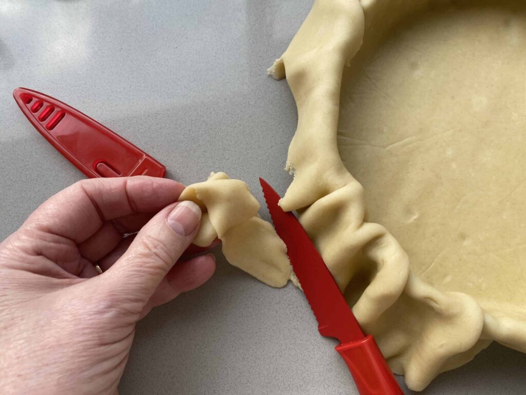 Red knife slicing Pastry dough in a tart tin