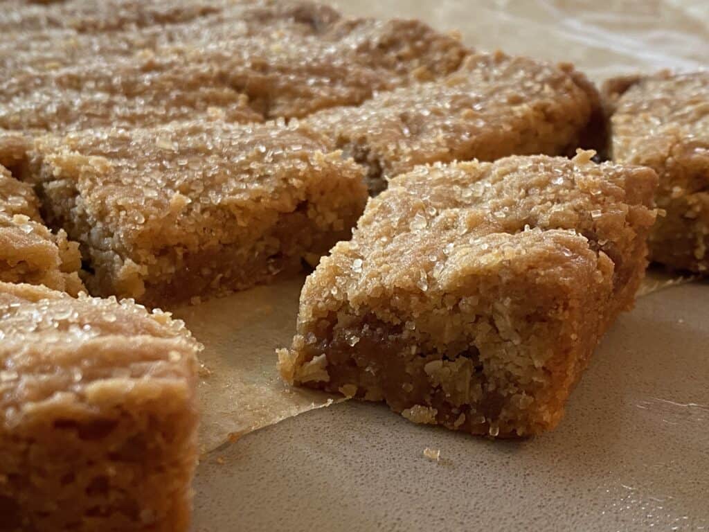 Slices of cookie bars on a sheet pf baking parchment