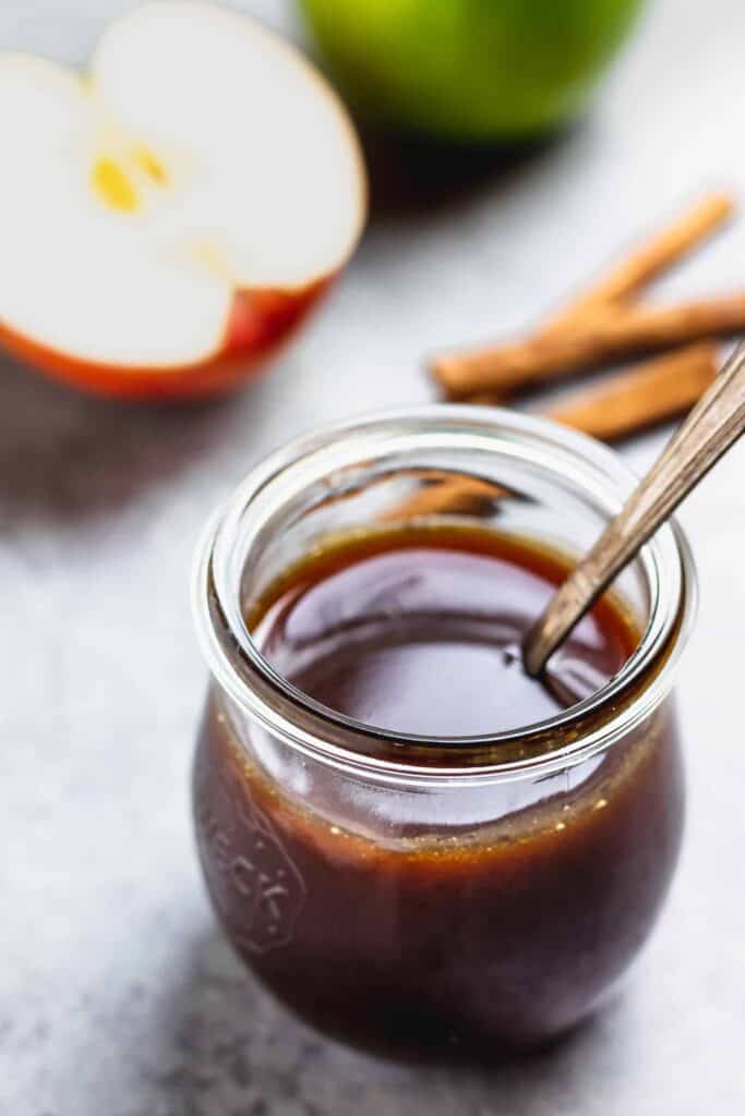 Caramel in a jar with a slice of apple on the side. 