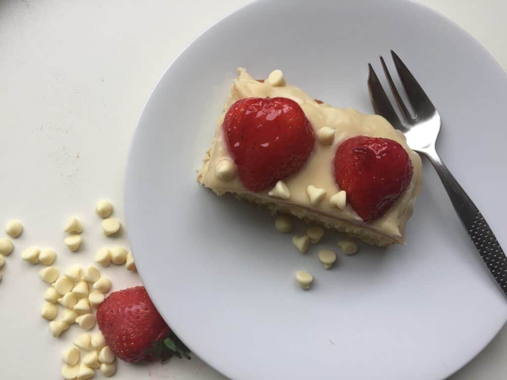 Slice of Vanilla Sheet cake with strawberries on a white plate