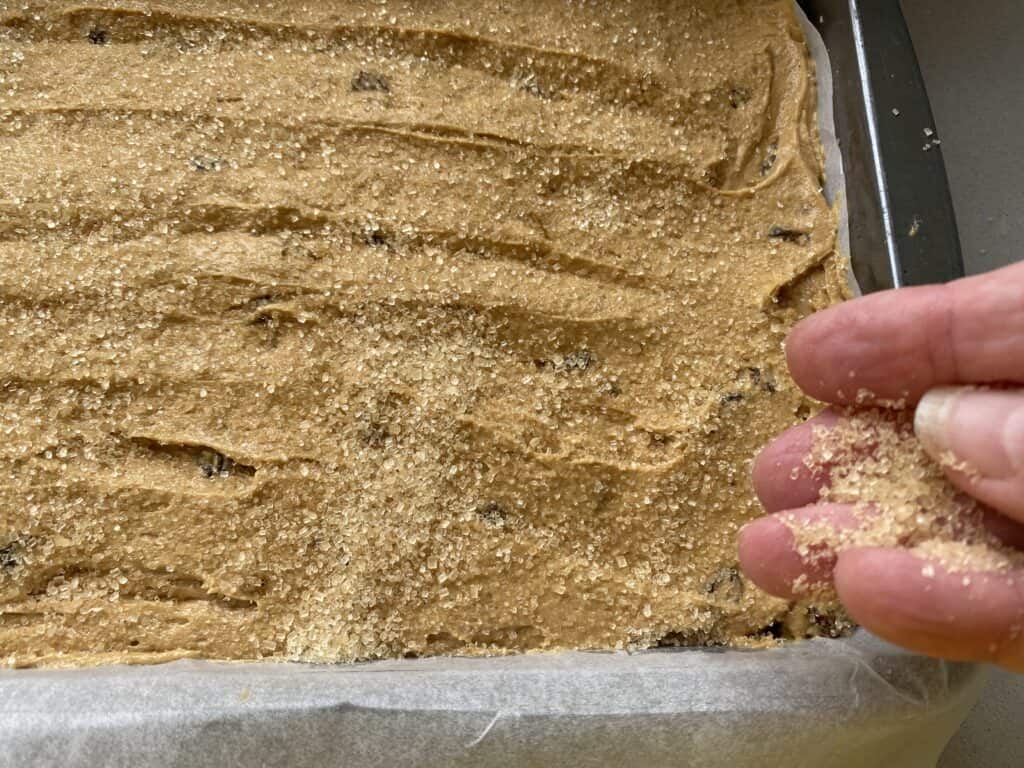 Scattering sugar over the top of a tray bake cake batter