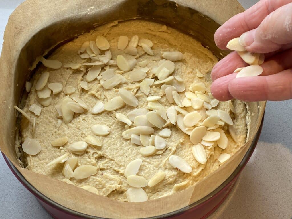 Cake batter in a cake tin with Flaked Almonds on top