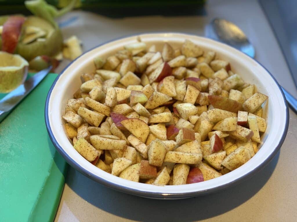 Chopped apples coated in spice placed in a pie dish