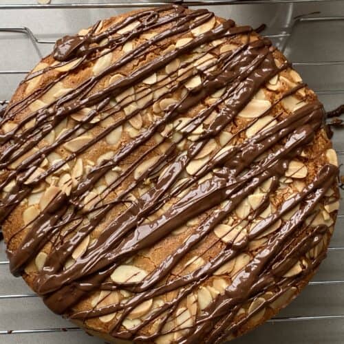 Ground Almond Cake with flaked almonds and chocolate Drizzle. on a cake rack