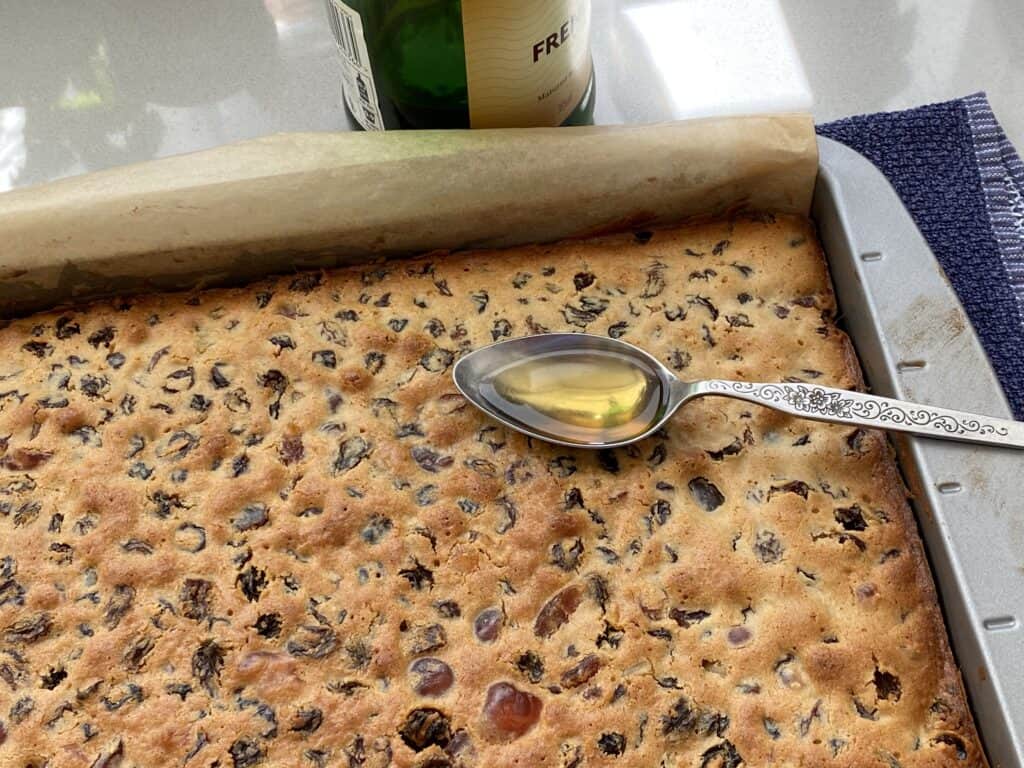 Spoon of brandy being poured over Christmas cake