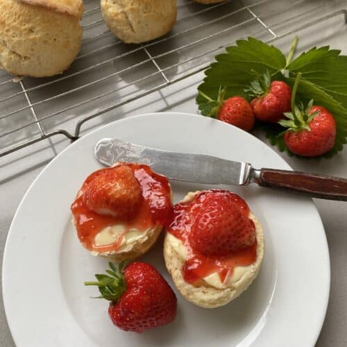 Sweet scones with butter and jam on a white plate